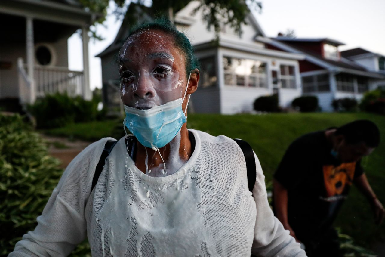 A protestor douses her face with milk after being exposed to tear gas fired by police.