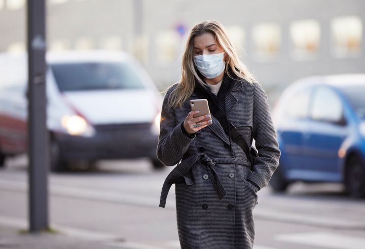 Young woman outside train station wearing a virus protective face mask