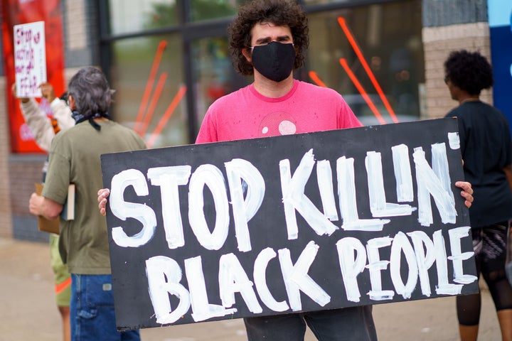 A man holds a "Stop Killing Black People" sign on May 26, 2020, near the area where Minneapolis police killed George Floyd. 