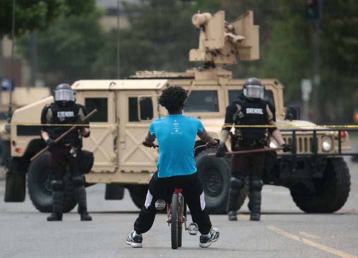 A man rides a bicycle up to a law enforcement checkpoint Friday in Minneapolis.