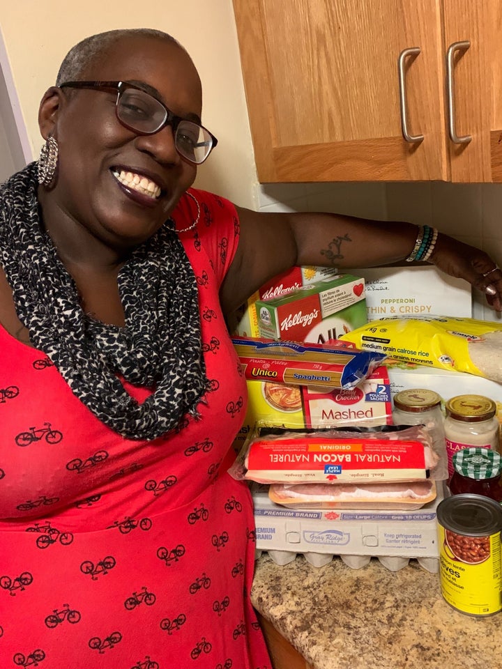 A volunteer poses with the contents of a care package, which include breakfast and hearty meal options.