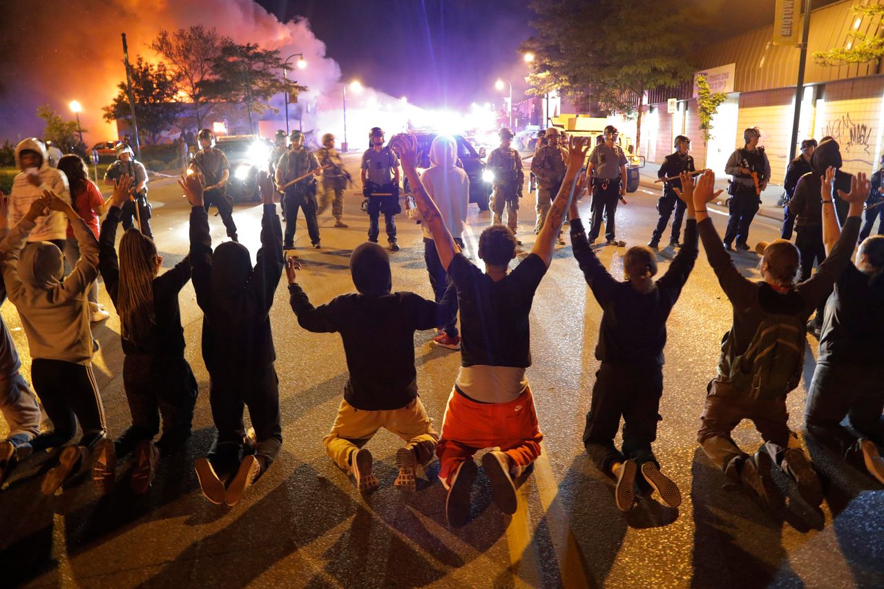 Demonstrators kneel before police in Minneapolis in the early hours of Saturday morning.