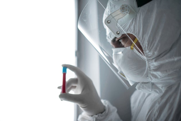 In a chemistry lab, a male researcher holds a tube with the coronavirus
