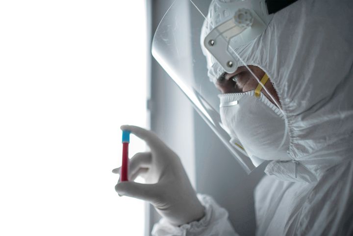 In a chemistry lab, a male researcher holds a tube with the coronavirus virus.