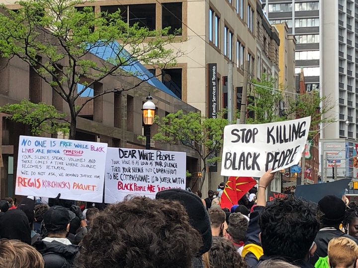 Protesters hold signs outside Toronto police Headquaters on May 30, 2020.