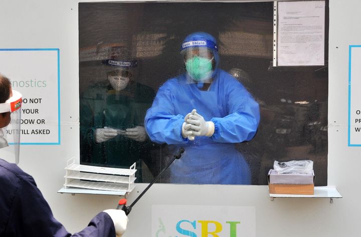 Staff sanitize themselves after taking a sample at a drive through testing booth installed by a private laboratory, on May 30, 2020 in Chandigarh, India. 