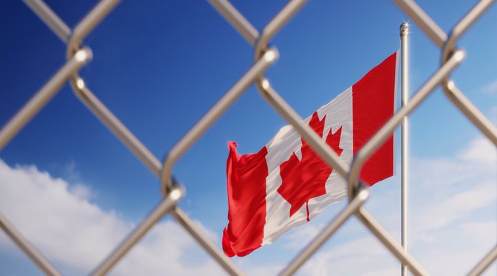 Fence in front of Canadian flag. Illegal immigration concept. Horizontal composition with copy space.