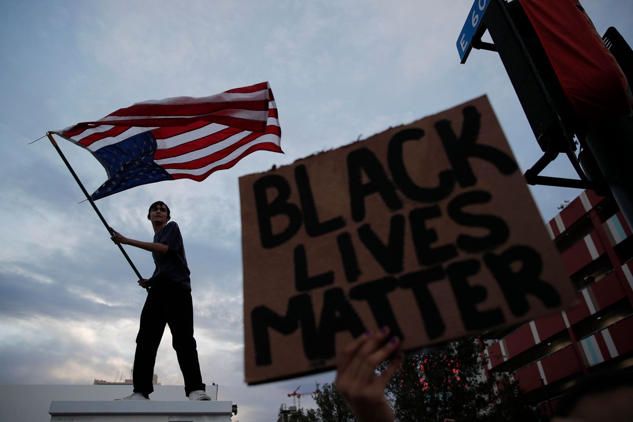 Λας Βέγκας: Ένας λευκός ανεμίζει τη σημαία των ΗΠΑ αναποδογυρισμένη σε διαδήλωση για τον Φλόιντ ενώ ένα πλακάτ δίπλα του γράφει "Black Lives Matter"