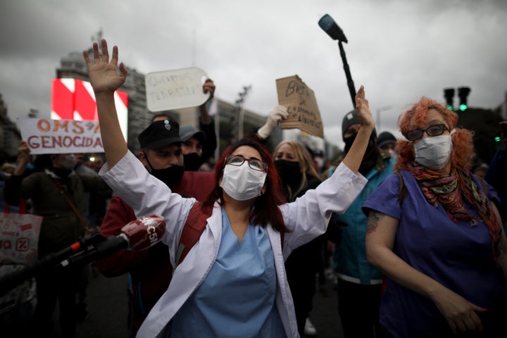 Doctors, front, demonstrate in favor of the government-ordered lockdown to help curb the spread of the new coronavirus while dueling protesters demand an end to the lockdown, in Buenos Aires, Argentina, Saturday, May 30, 2020. (AP Photo/Natacha Pisarenko)