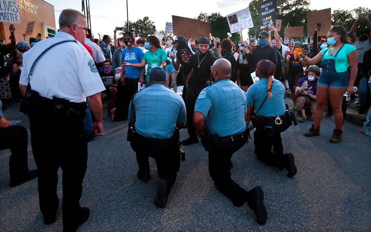 Police officers from Ferguson, Missouri, join protesters to remember George Floyd by taking a knee in the parking lot of the police station on Saturday.