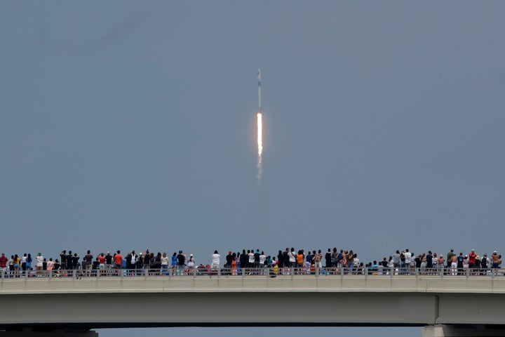 Spectators watch from a bridge in Titusville, Fla. as SpaceX Falcon 9 lifts off with two NASA astronauts on Saturday.