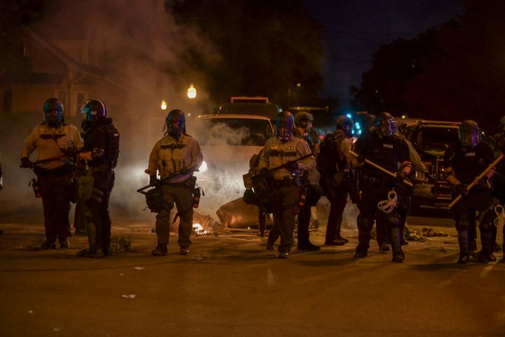 Police are seen armed with batons after protesters violated a curfew in effect in Minneapolis on Saturday.