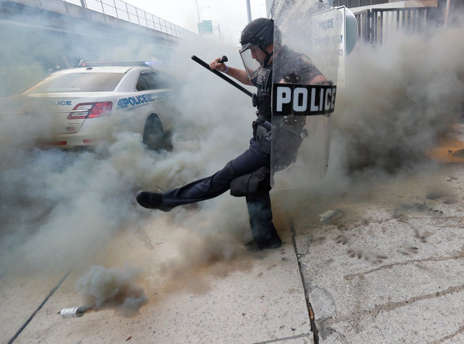 A policeman kicks back a tear gas canister during a demonstration next to the city of Miami Police Department on May 30, 2020.