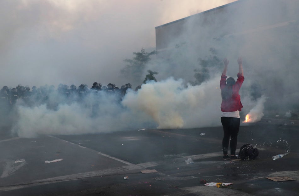 A demonstrator holds her hand up as police advance during a protest against the killing of George Floyd on May 30, 2020 in Minneapolis, Minn. Former Minneapolis police officer Derek Chauvin has been charged with third-degree murder and manslaughter, accused of kneeling on Floyd's neck as he pleaded about not being able to breathe.