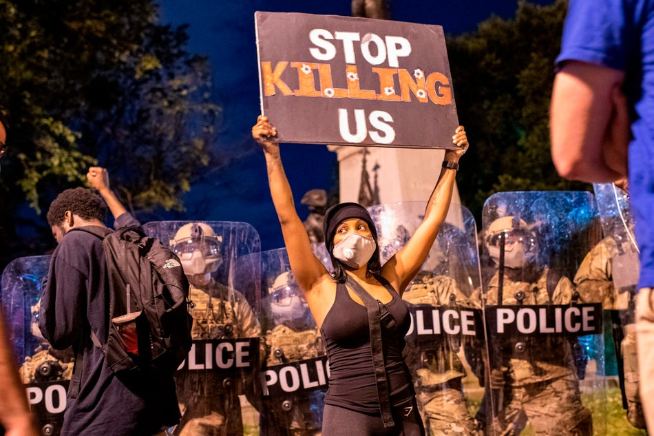 A demonstrator holds a sign reading "Stop Killing Us" in front of a police line outside of the White House on May 30, 2020.