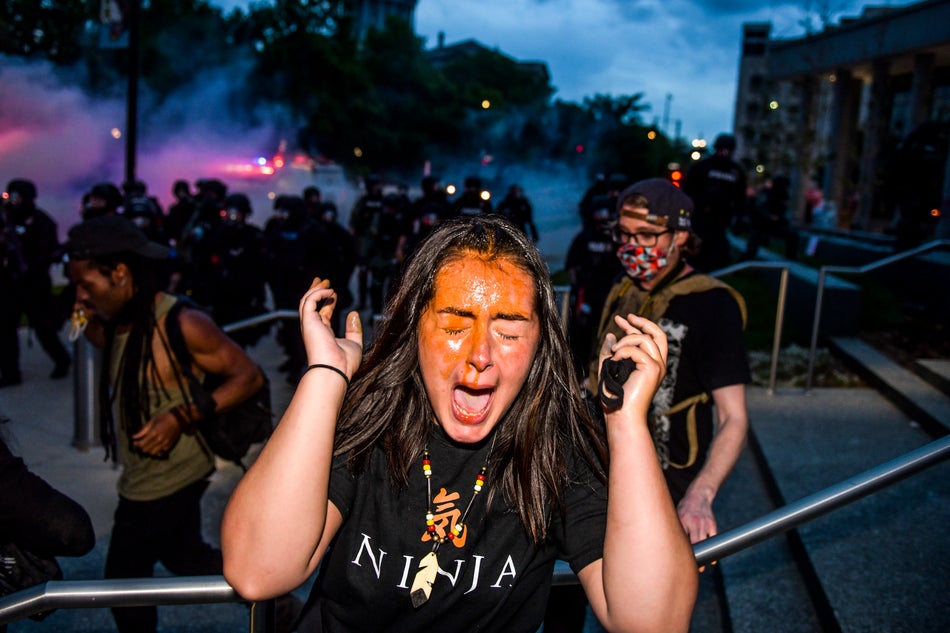 A woman reacts after being hit by pepper spray next to the Colorado State Capitol on May 30, 2020 in Denver.