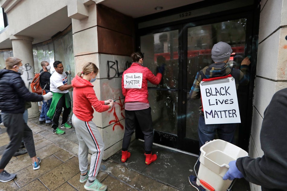 Volunteers work side-by-side cleaning graffiti off of a store on May 30, 2020 in Seattle following protests.