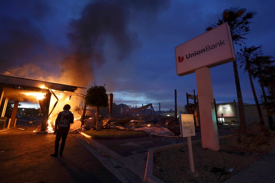 A man looks on as a bank burns after a protest over the death of George Floyd on on May 31, 2020 in La Mesa, Calif.