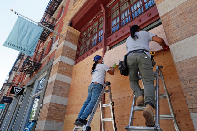 Workers board up the windows of a Tiffany's store in SoHo, New York City, on Sunday.