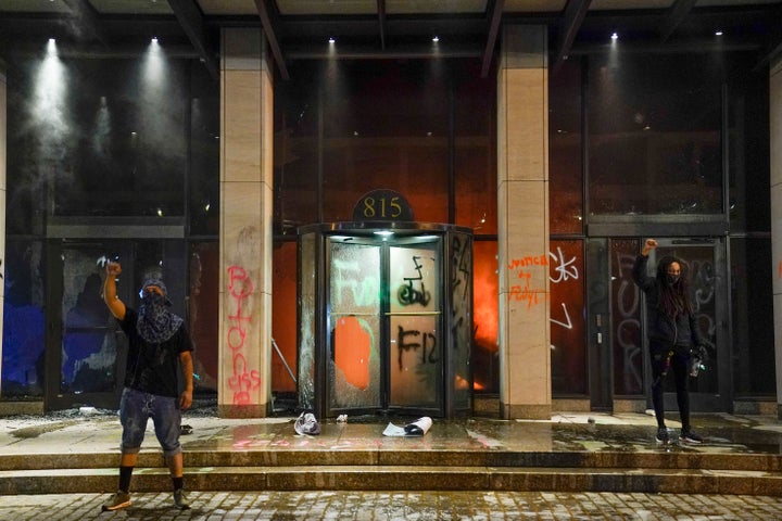 Demonstrators hold their fist in the air while a fire burns inside the AFL-CIO headquarters.