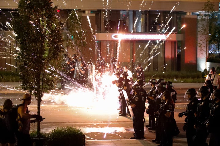A firework explodes by a police line as demonstrators gather to protest the death of George Floyd.