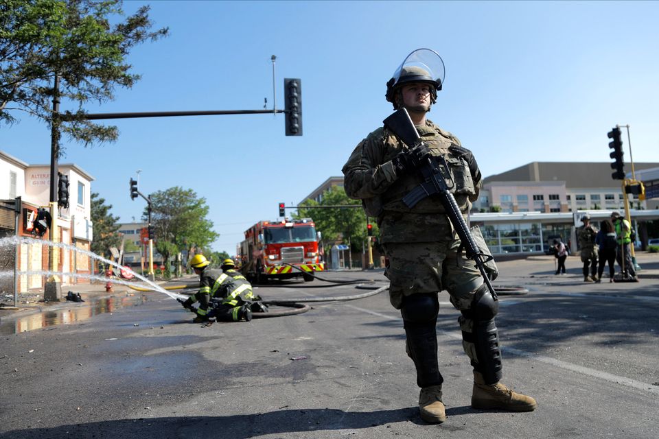 A member of the Minnesota National Guard assists firefighters putting out a structure fire on Saturday.