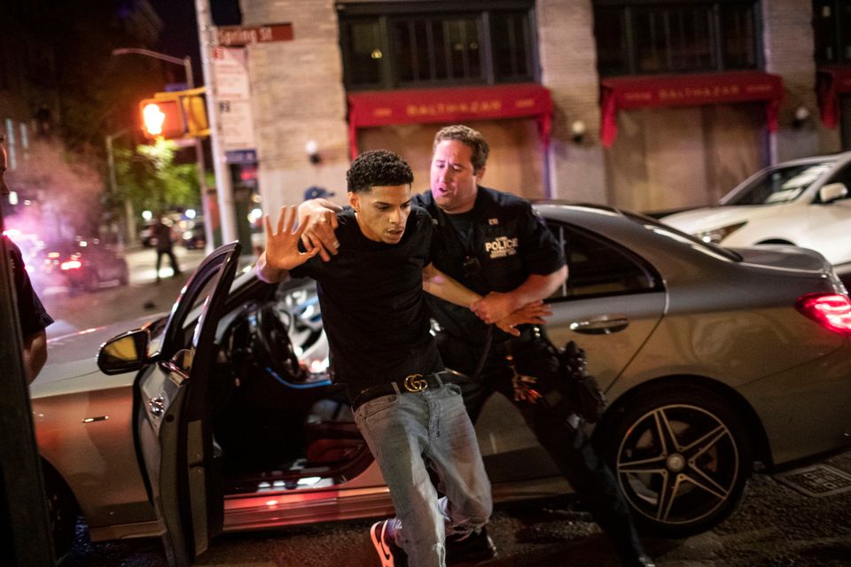 A police officer pulls a driver from a vehicle during looting in the SoHo shopping district on Sunday evening.