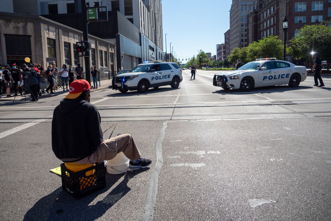 A street musician plays the drums in an intersection as demonstrators and officers from the Hamilton County Sheriffs Department and Cincinnati Police Department stand-off on Sunday.