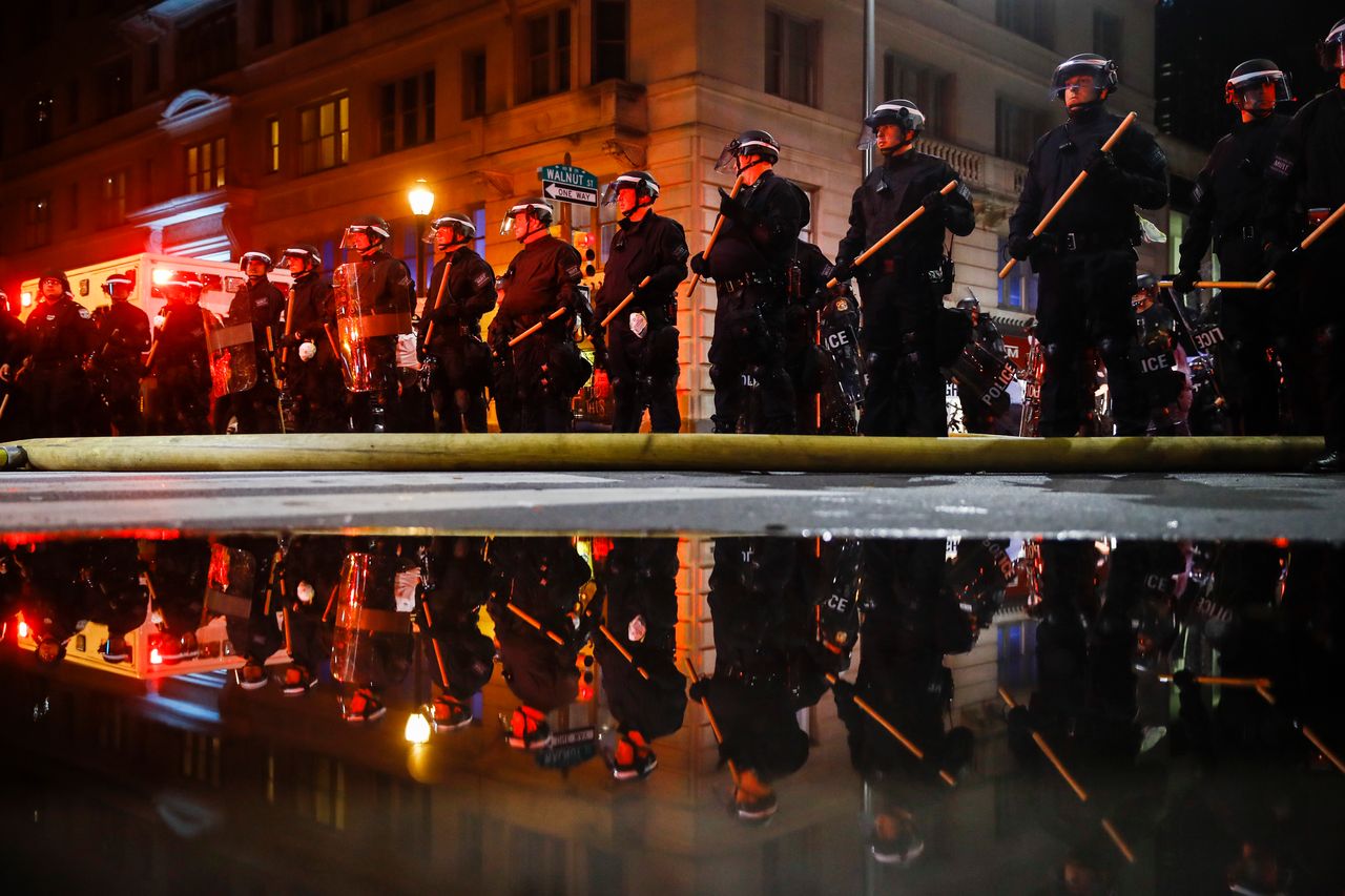 Police are reflected as they stand guard in Philadelphia on Saturday.