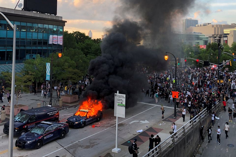 An Atlanta Police car burns as people protest near CNN Center in Atlanta.