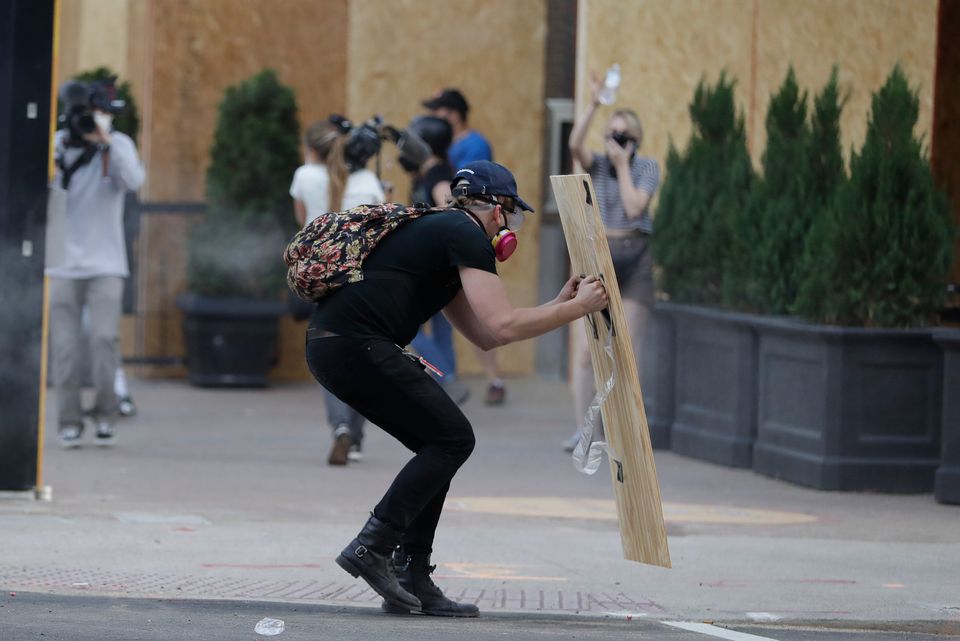 A protester hides behind a board after police fired tear gas during a protest over the deaths of George Floyd on Saturday.