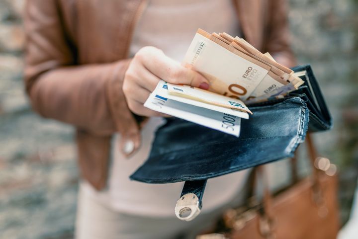 Woman holding in hands wallet with euro money. City girl is taking out money from wallet