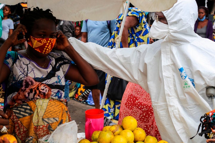 A street shop-keeper is receiving a face mask as a preventive measure against the spread of the COVID-19 coronavirus from a F