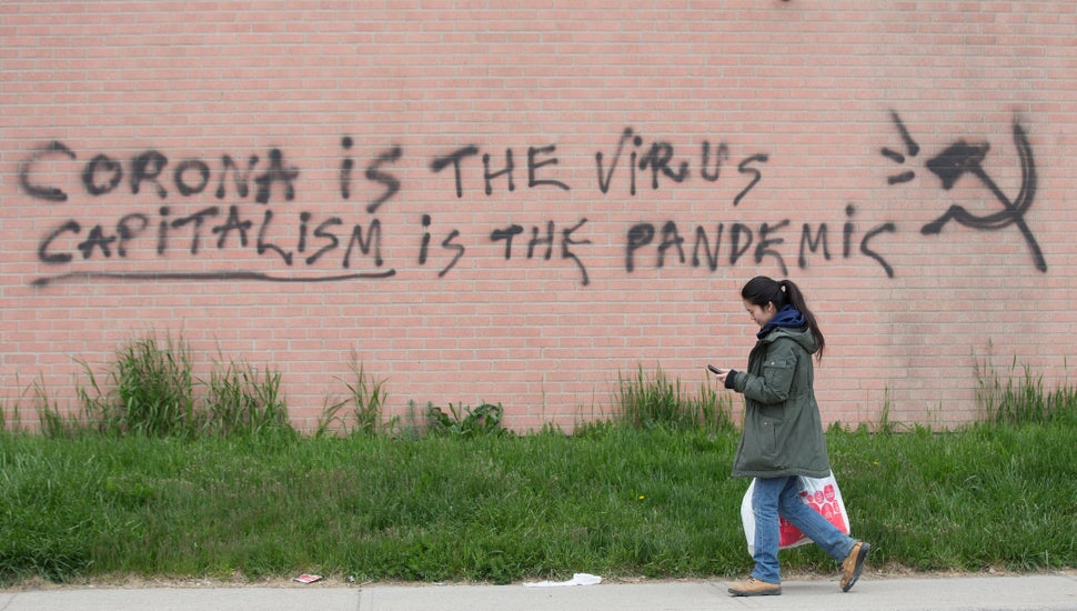 A woman walks by a message scrawled on the side of a Toronto business on May 14,