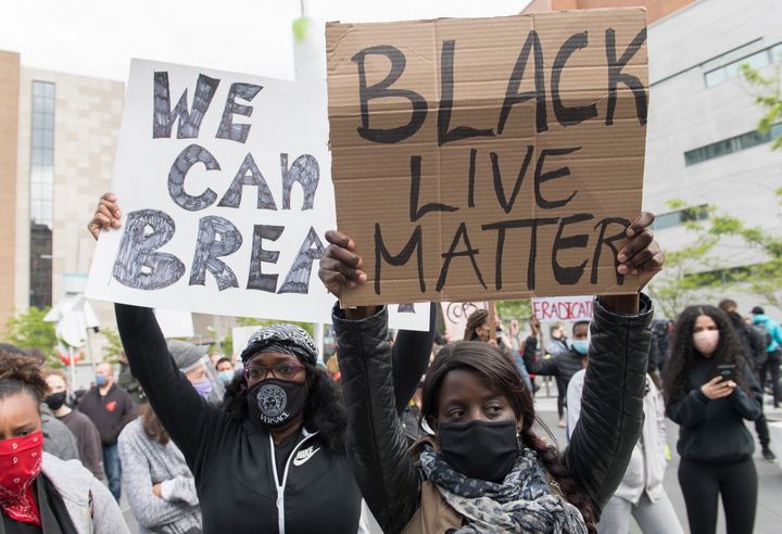 People hold up signs during a demonstration where they called for justice for George Floyd and all victims of police brutality in Montreal on May 31, 2020.