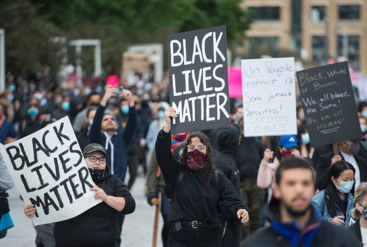 People hold up signs during a demonstration where they called for justice for George Floyd and all victims of police brutality in Montreal on May 31, 2020.