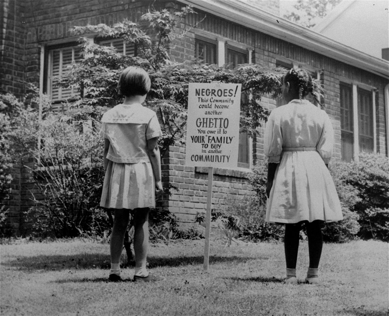Απρίλιος 1962 - Μια αφροαμερικανή και ένα λευκό κορίτσι κοιτάζουν μια πινακίδα στο Long Island η οποία γράφει: «Νέγροι! Αυτή η κοινότητα μπορεί να εξελιχθεί σε ένα ακόμη γκέτο. Το οφείλεις στην οικογένειά σου να αγοράσεις σε άλλη κοινότητα». Επρόκειτο για μια προσπάθεια να αποτρέψουν τους αφροαμερικανούς από το να υπερβούν αριθμητικά τους λευκούς σε περιοχές όπου οι πόλεις ήταν μικτές.