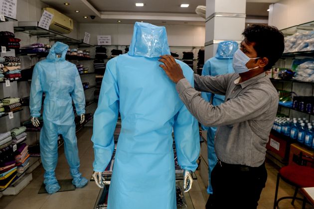 A shopkeeper arranges a protective suit for sale on a mannequin at a garment shop after the government...