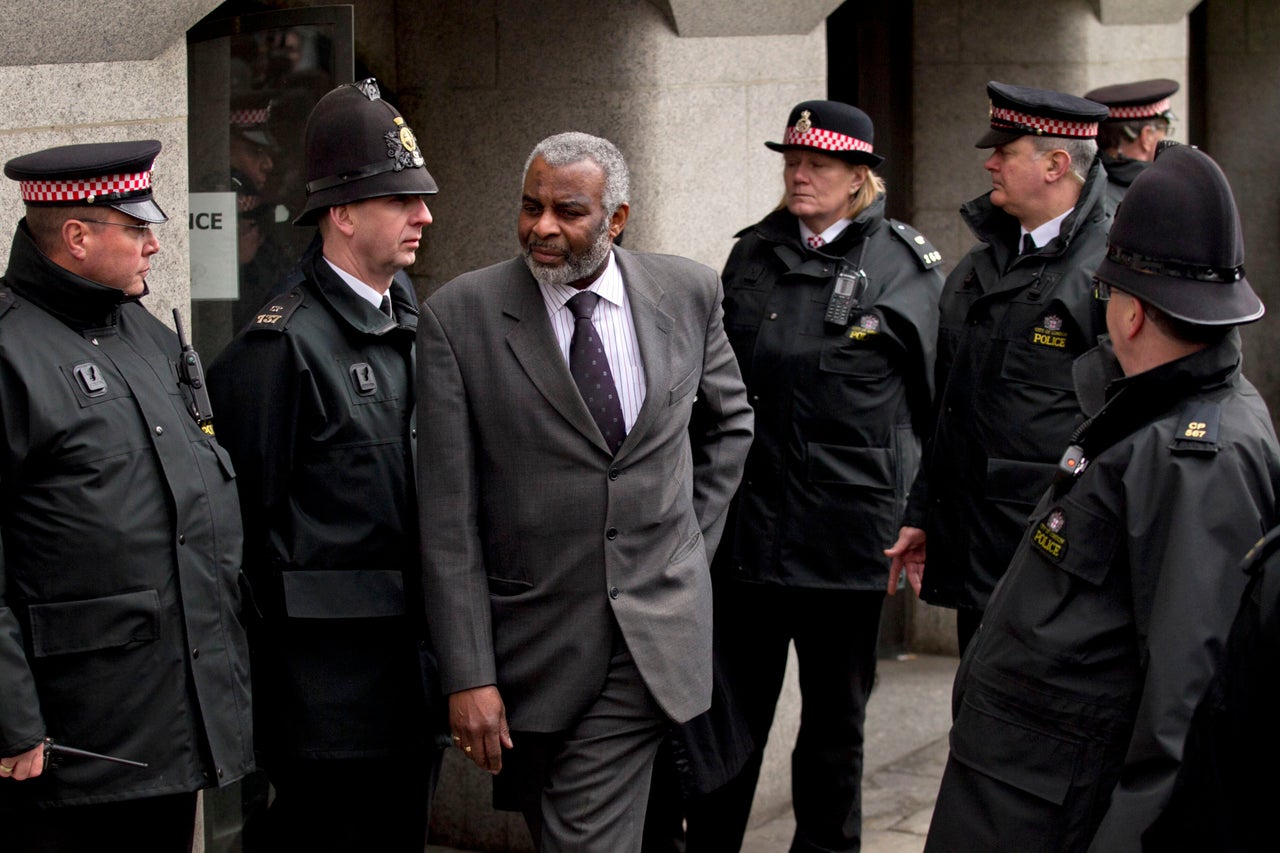 Neville Lawrence, centre, the father of murdered black teenager Stephen Lawrence, walks through police officers to speak to the media outside the Old Bailrey after Gary Dobson and David Norris were sentenced for their part in the murder