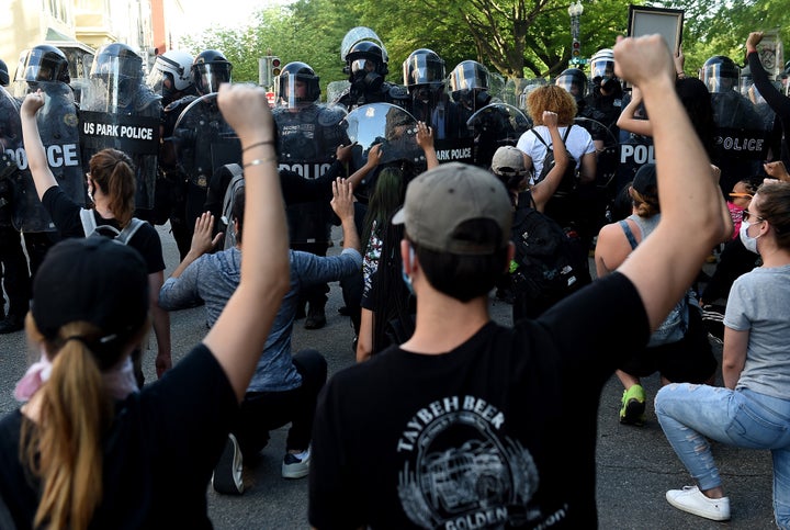 Protesters kneel and hold up their hands in front of a row of police during a demonstration against police brutality at a park near the White House on June 1 in Washington, D.C.