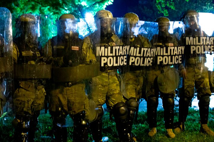Military police officers watch demonstrators as they chant outside of the White House on May 30 in Washington, D.C., during a