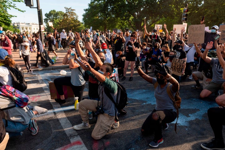 Protestors take a knee and raise their hands as they face riot police near the White House on June 1 as demonstrations against George Floyd's death continue.