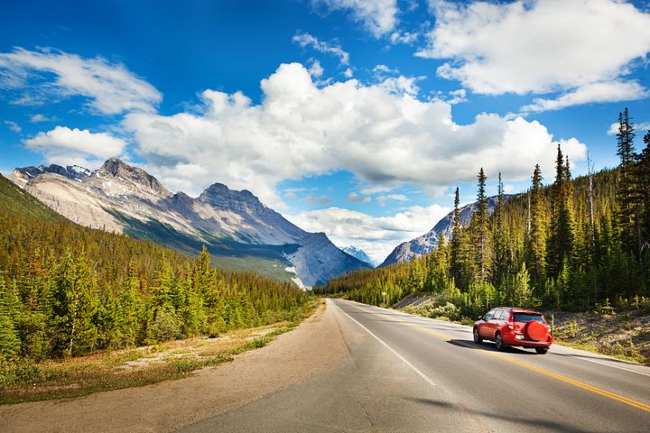 A car drives through Banff National Park in Alberta.