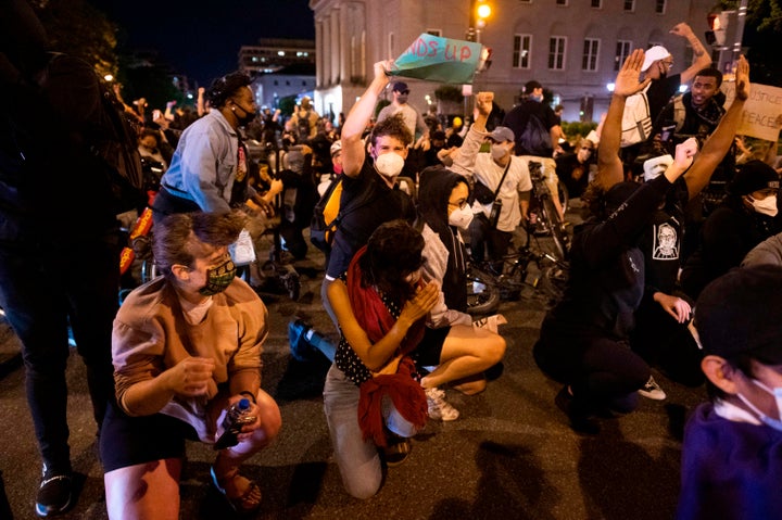 Demonstrators steady themselves as a military helicopter flies low over the crowd in Washington, D.C. during a protest over the death of George Floyd on June 1, 2020. 