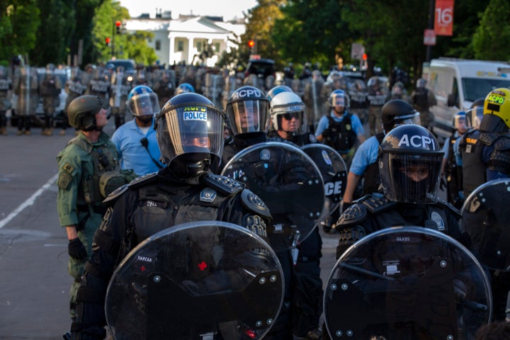 The White House looms in the background behind a line of law enforcement officers wearing riot gear as they push back demonstrators Friday in Washington.