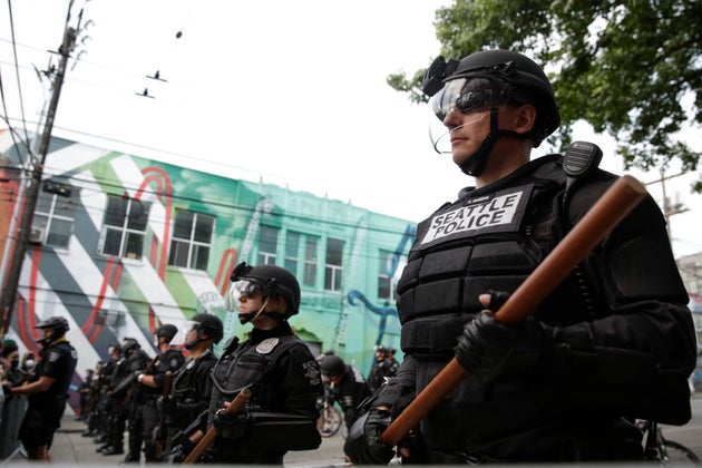 Seattle Police stand guard outside a precinct on Monday as people In Seattle joined in the nationwide...