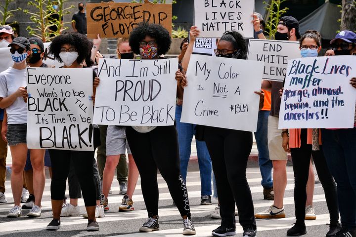 People hold up signs during a Black Lives Matter demonstration outside police headquarters in downtown Los Angeles