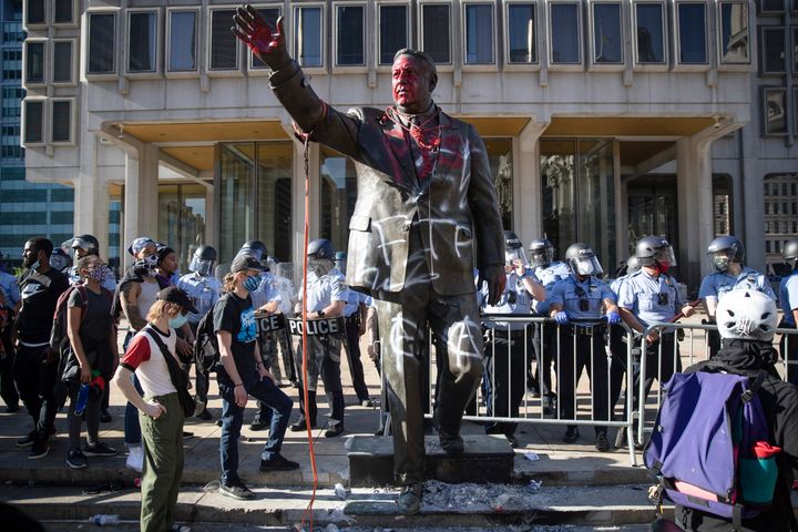 Police stand near the former mayor's vandalized statue on May 30 during protests over the death of George Floyd.