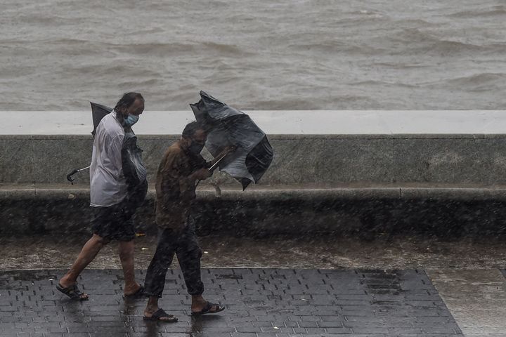 Two men carrying umbrellas walk on the Marine Drive in Mumbai on June 3, 2020,