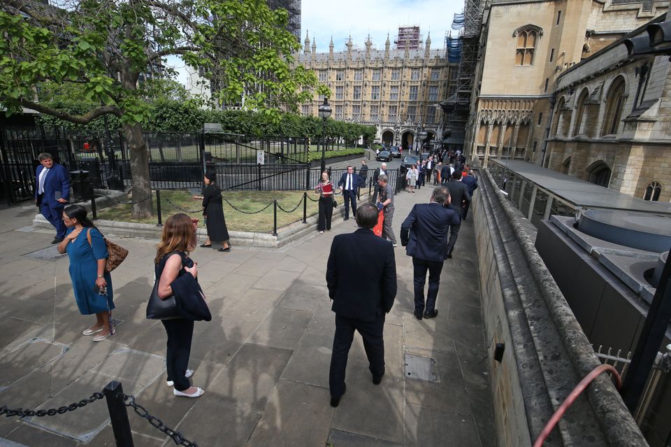 MPs queue outside the House of Commons in Westminster, London, as they wait to vote on the future of proceedings, amid a row over how Commons business can take place safely